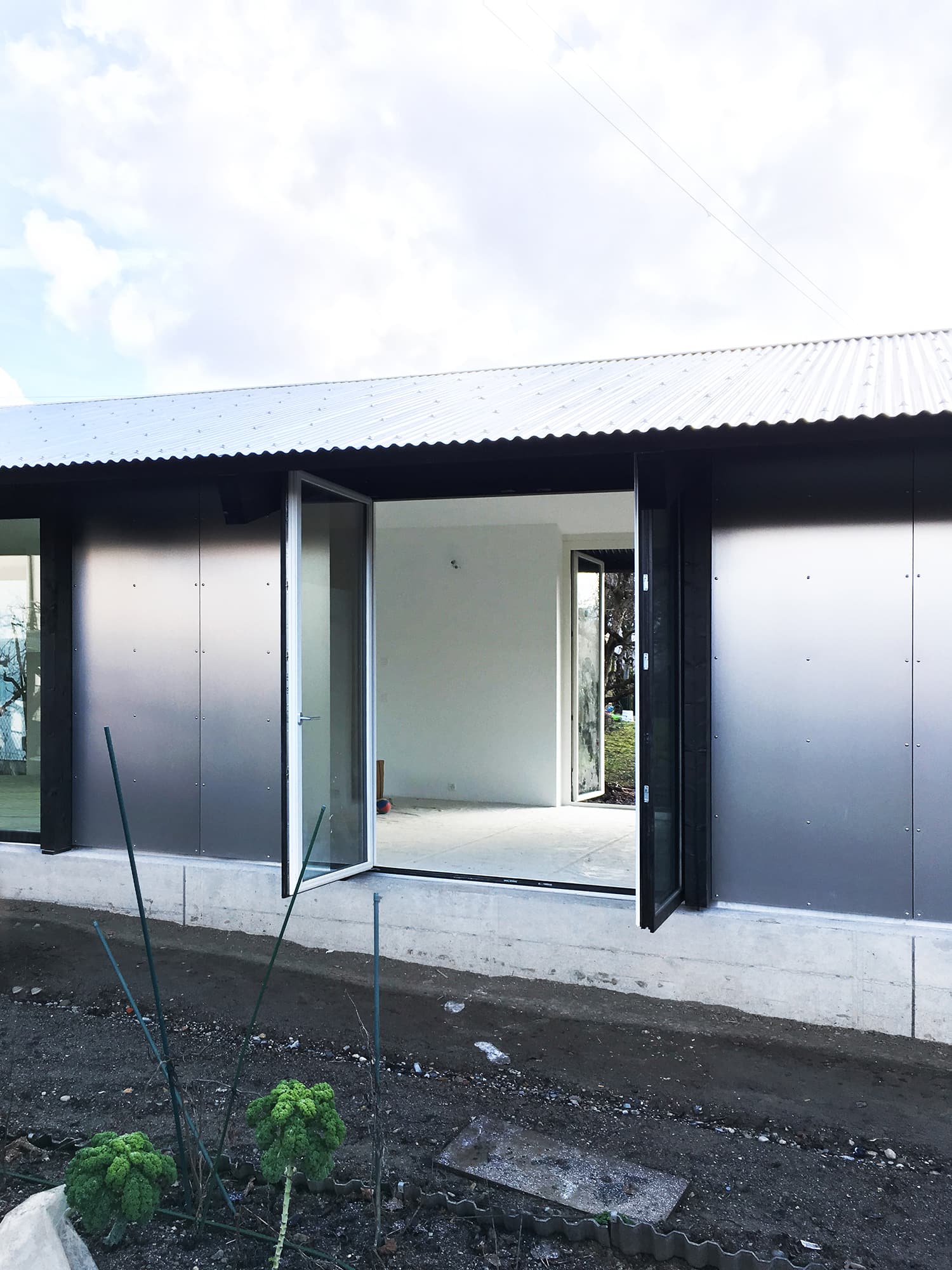 The Permanent Weekend House is a thin and long construction, extending an old chalet through its garden